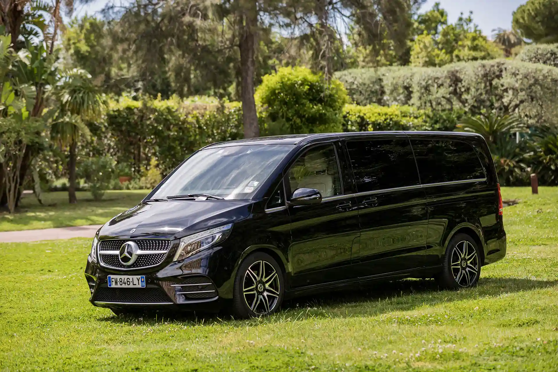 Mercedes-Benz Classe V noire stationnée dans un cadre verdoyant. Minivan de luxe idéal pour le transport VIP et les déplacements en groupe avec chauffeur privé.