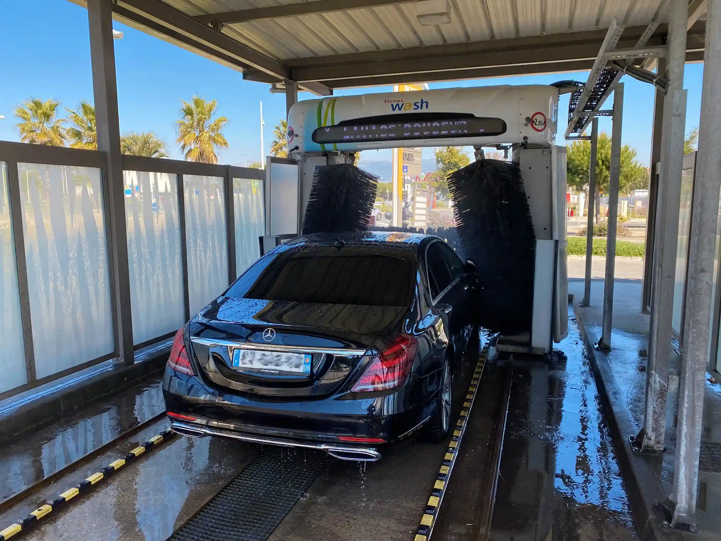 Berline Mercedes noire en cours de nettoyage dans une station de lavage – entretien rigoureux du véhicule pour un service de transport privé impeccable.